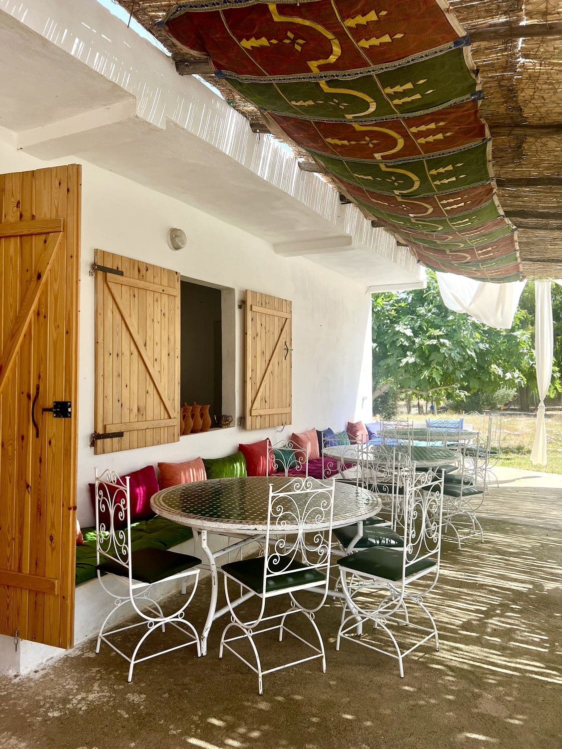 La terrasse du parc, tables blanches et coussins sous le toit de roseaux