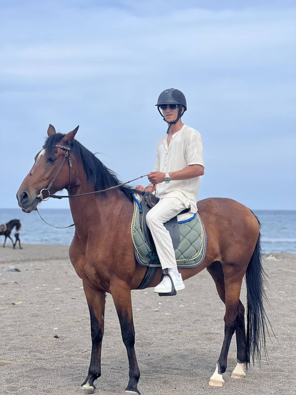 Un cavalier sur un cheval bai, au bord de la mer